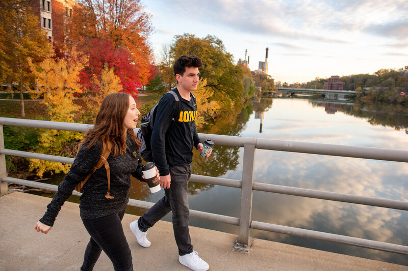 Students on campus crossing a river bridge in the fall. 